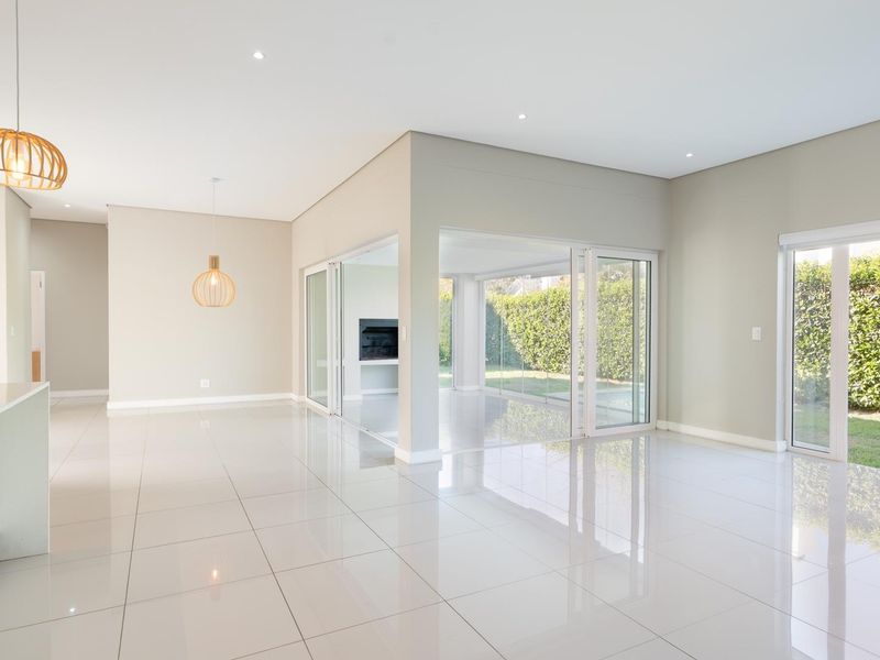 Spacious open-plan living area featuring polished porcelain tiles, recessed lighting, and large sliding glass doors providing seamless access to the garden and patio.