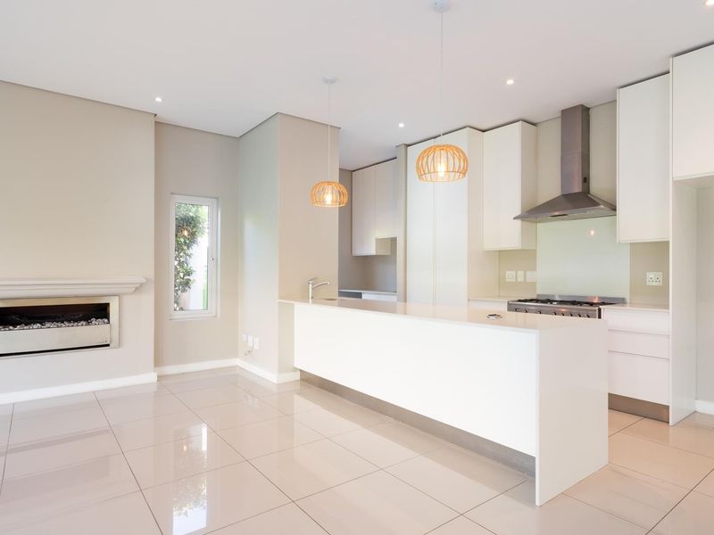 Modern open-plan kitchen and living area featuring a sleek kitchen island, built-in fireplace, and high-quality tiled flooring throughout.