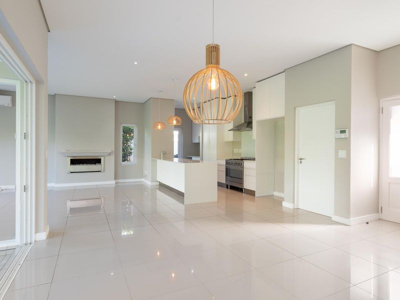 Spacious open-plan living and kitchen area featuring modern tiled floors, a built-in fireplace, and a sleek kitchen with integrated appliances.