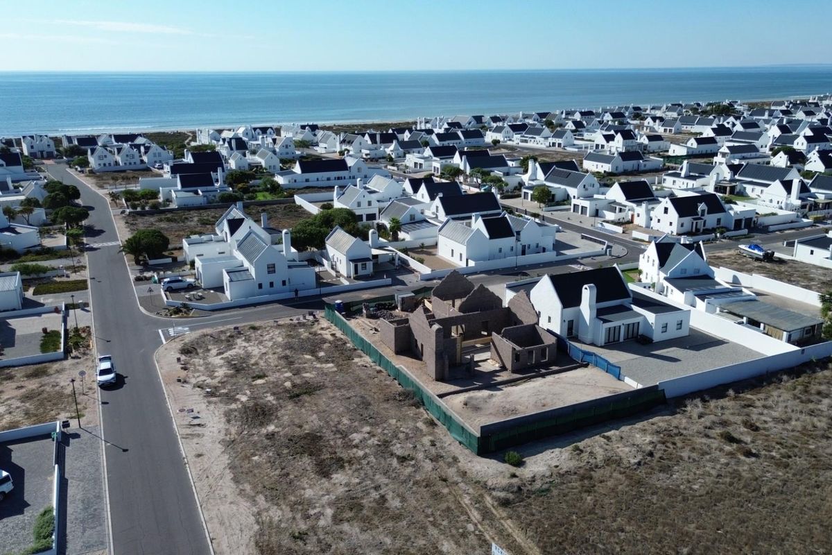 Aerial view of a residential development featuring a vacant plot with a partially constructed brick building structure.