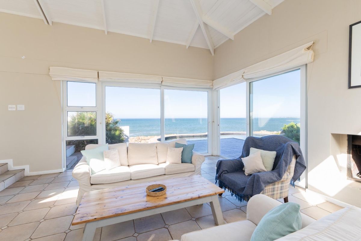 Bright living room featuring high vaulted ceilings, tiled flooring, and expansive sliding glass doors offering panoramic ocean views.