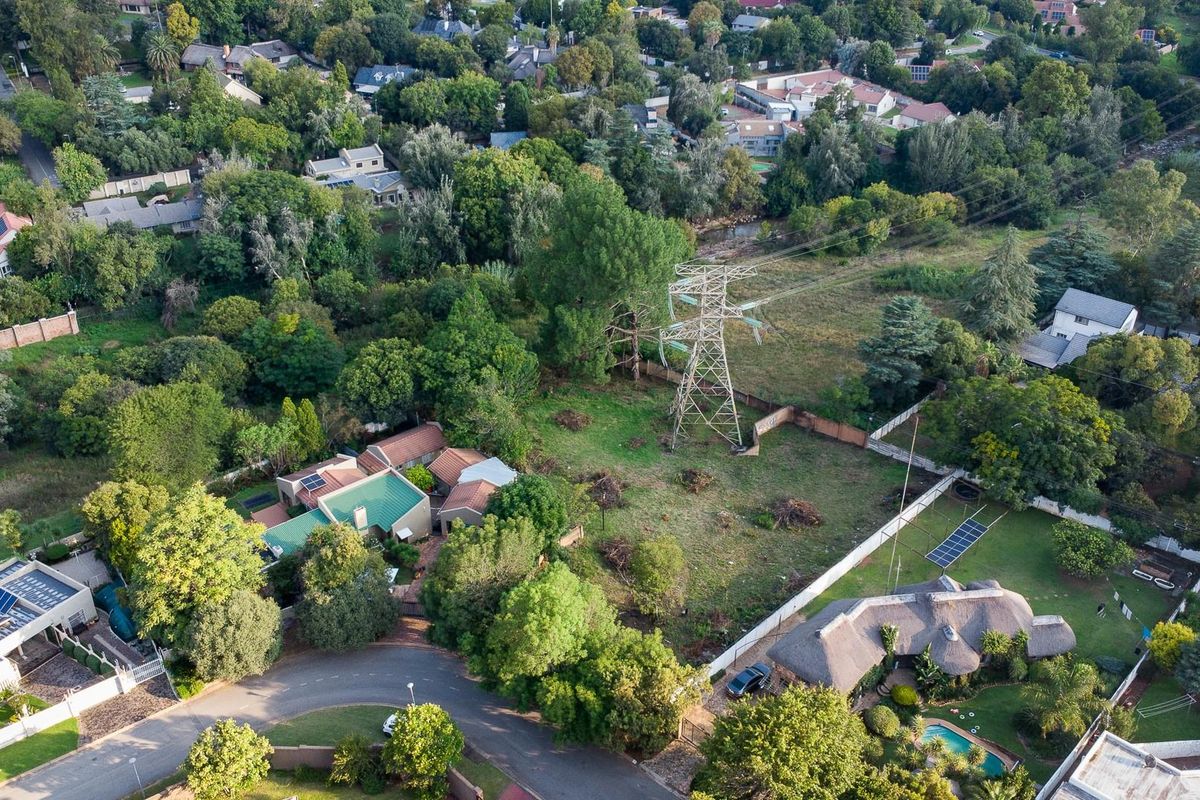 Aerial view of a residential vacant land plot situated in a established neighborhood, featuring mature trees and proximity to local infrastructure.