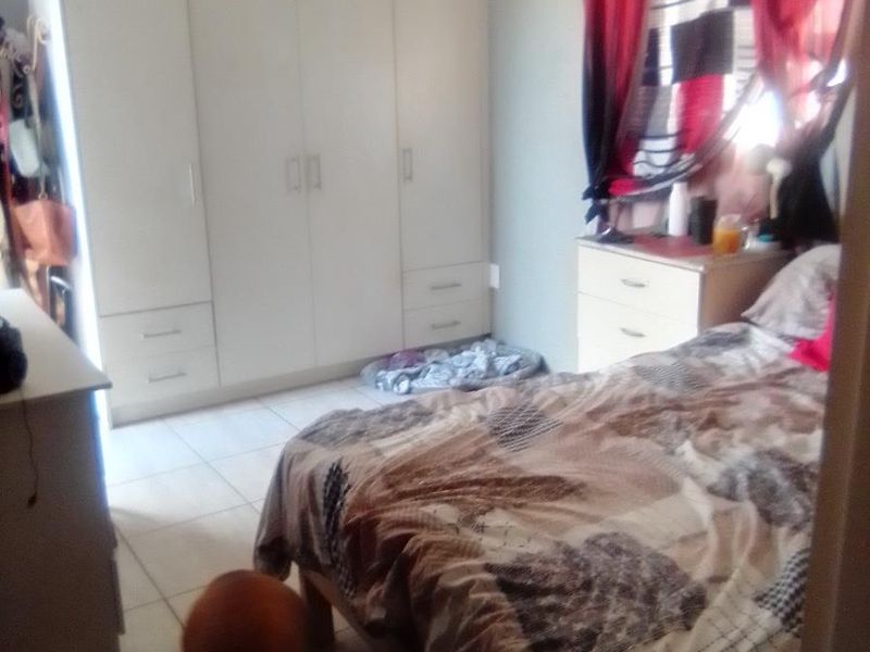 A bedroom featuring built-in cupboards and tiled flooring.