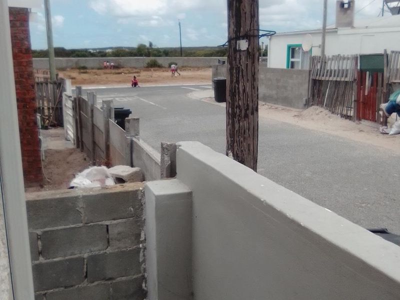 View from the property looking out towards the street, featuring a paved area, boundary walls, and surrounding residential neighborhood.