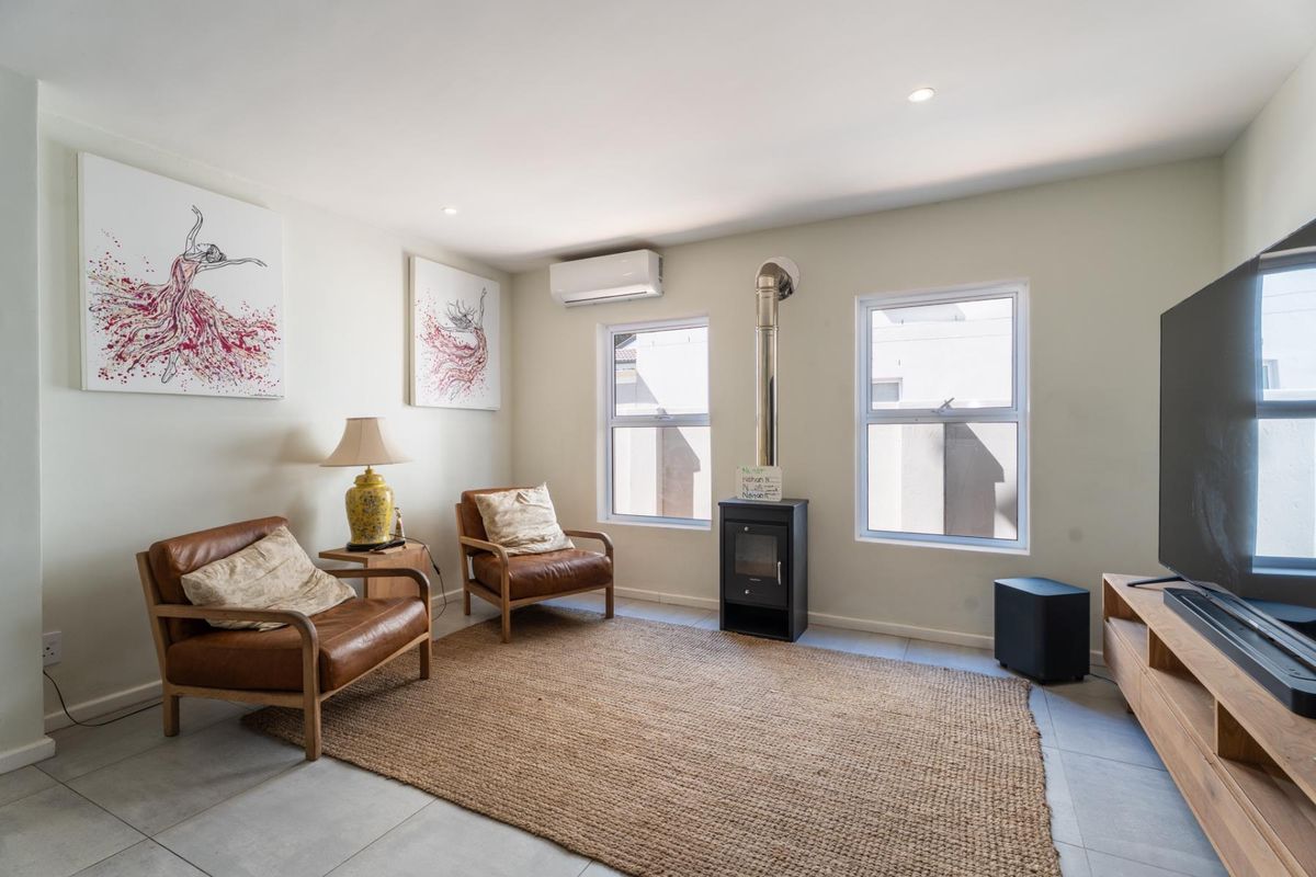 A bright living room featuring tiled flooring, a built-in fireplace, and a wall-mounted air conditioning unit.