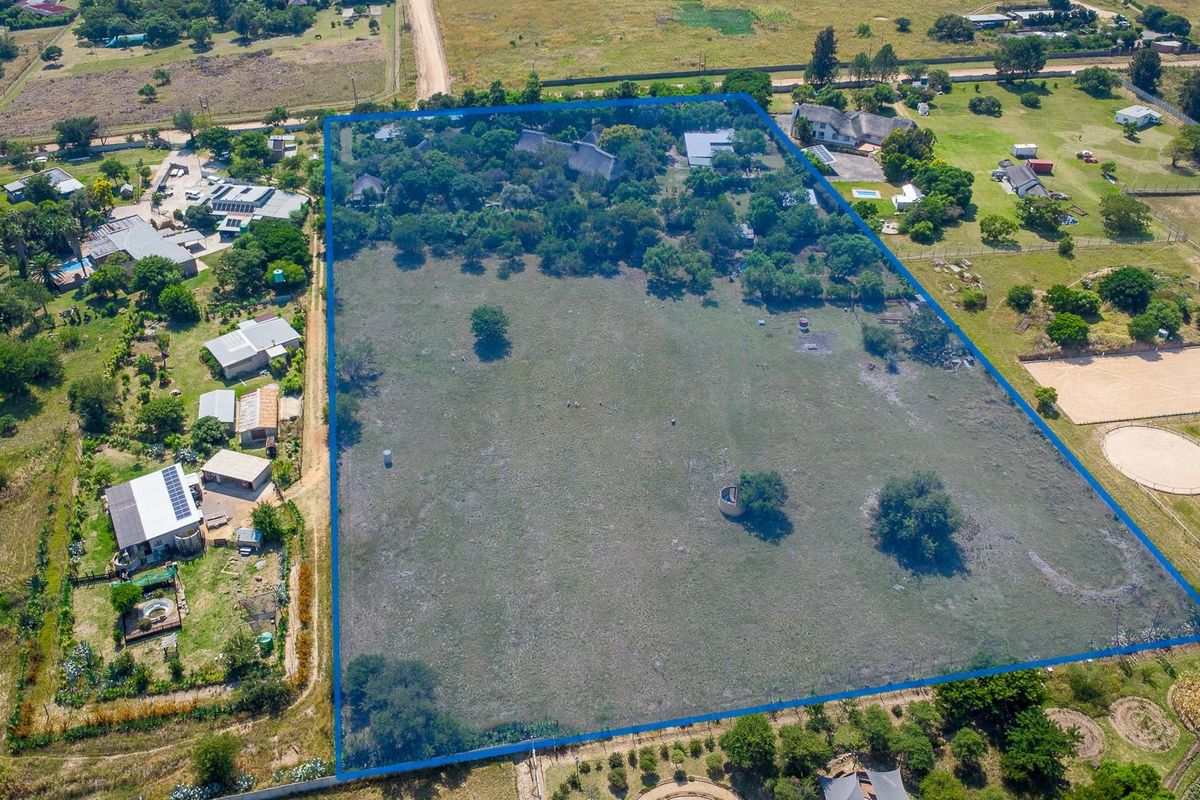 Aerial view of a large, expansive residential plot featuring established trees and open land, highlighting the property boundaries and surrounding neighborhood context.