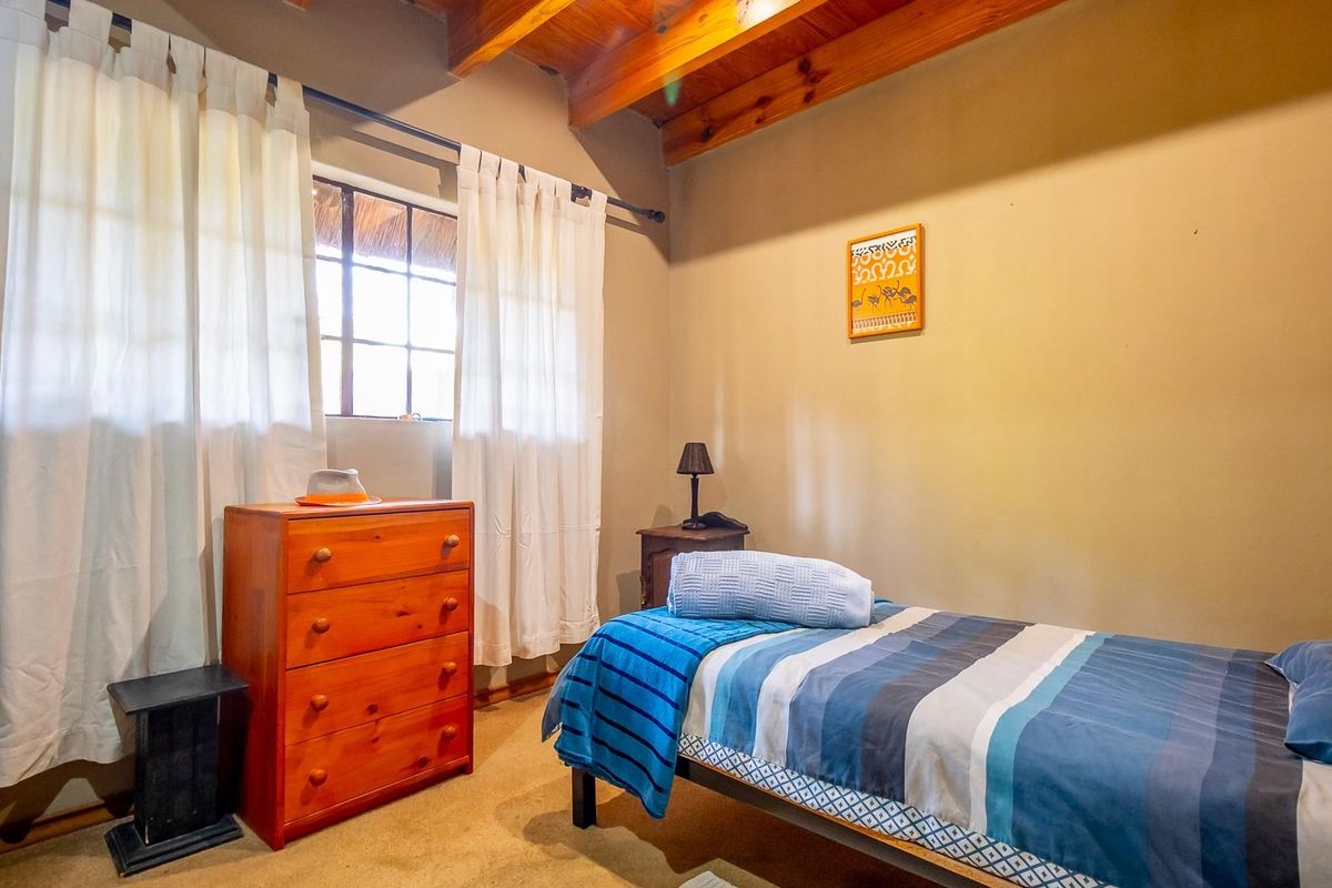 A cozy bedroom featuring exposed timber ceiling beams and a window with natural light.