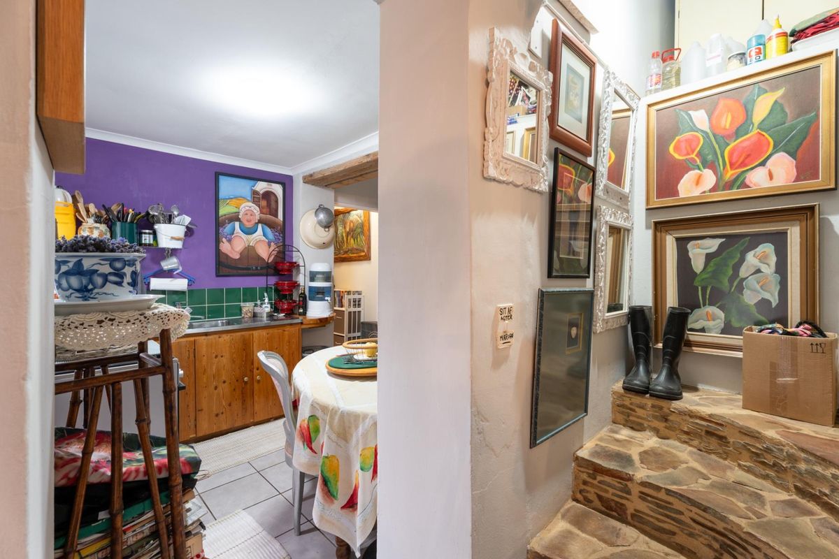 A view into a kitchen area featuring wooden cabinetry, tiled splashbacks, and a stone-tiled staircase leading to an adjacent level.