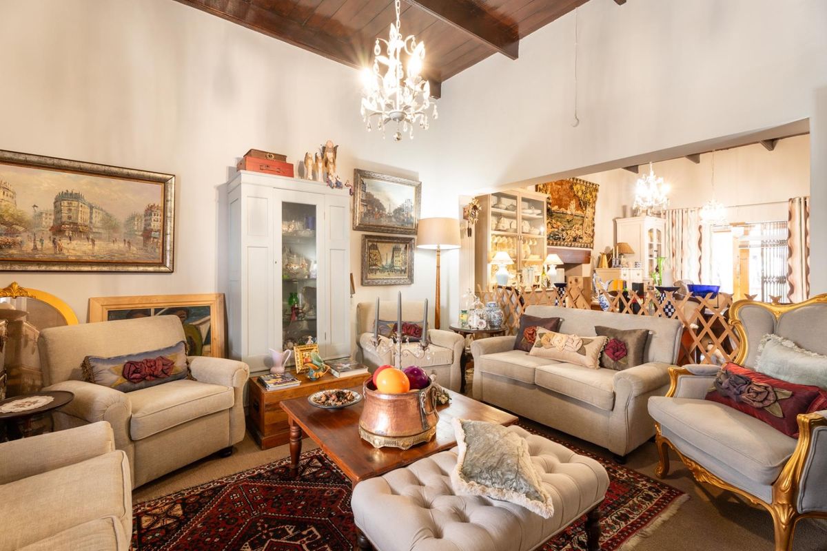 A spacious living room featuring high vaulted ceilings with exposed timber beams and a classic chandelier, creating an elegant and inviting atmosphere.