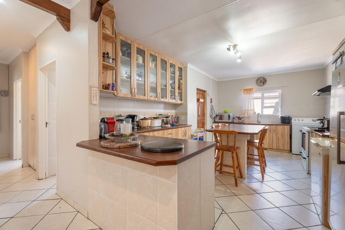 A functional kitchen featuring light wood cabinetry, a central island with breakfast seating, tiled flooring, and a tiled backsplash.