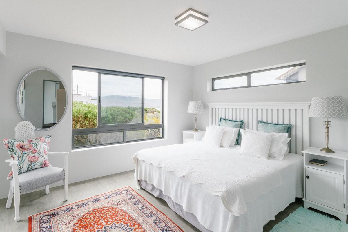 A bright and well-maintained bedroom featuring large sliding windows, a clerestory window, and neutral finishes, offering a clean and inviting atmosphere.