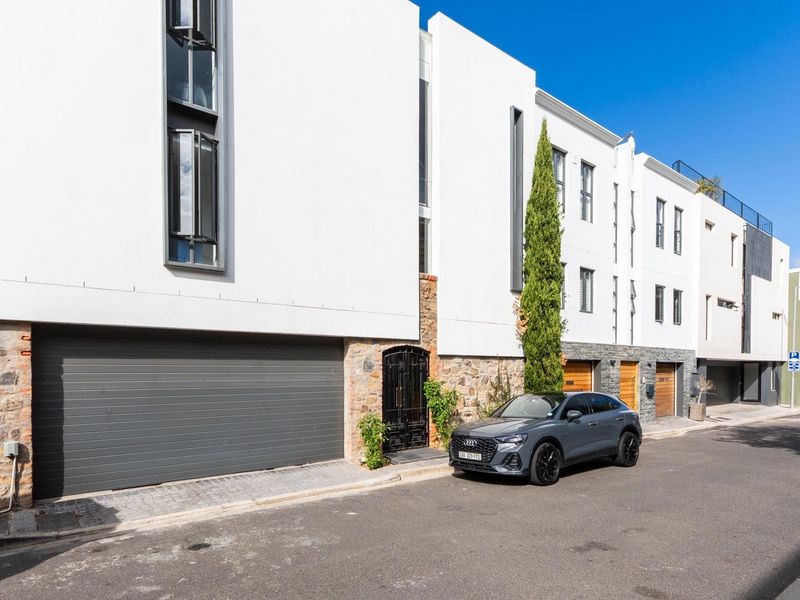 Modern multi-level townhouse facade featuring a large automated garage door, stone cladding accents, and contemporary architectural design.