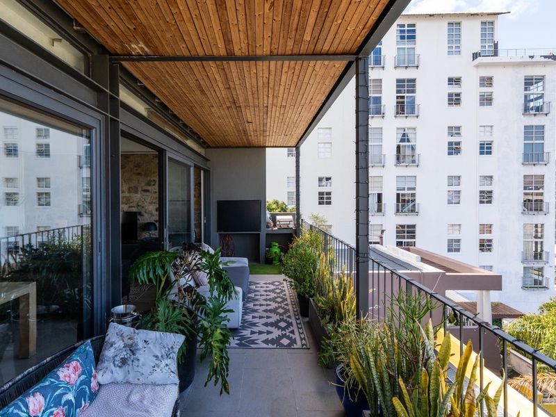 A covered balcony featuring a timber-clad ceiling, metal railings, and large sliding glass doors, offering an elevated urban view.