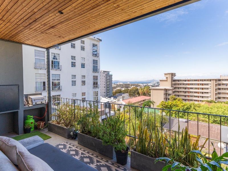 A covered balcony featuring a timber-clad ceiling, metal railings, and an integrated built-in barbecue area, offering elevated urban views.