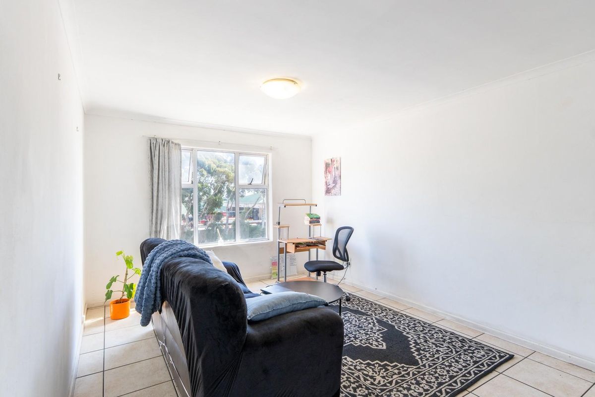 A bright living room featuring tiled flooring and a large window providing natural light.