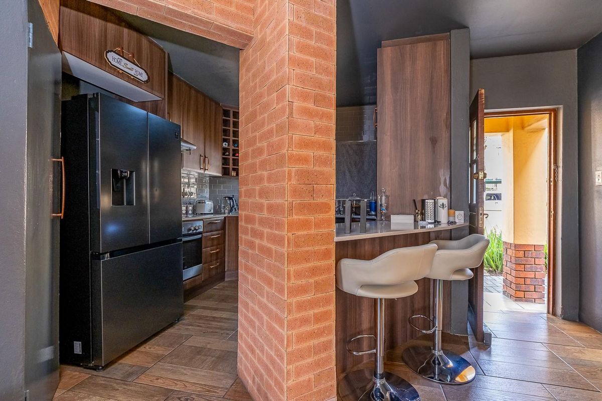 A functional kitchen featuring wood-look cabinetry, a breakfast bar with a brick pillar, and direct access to an outdoor area.