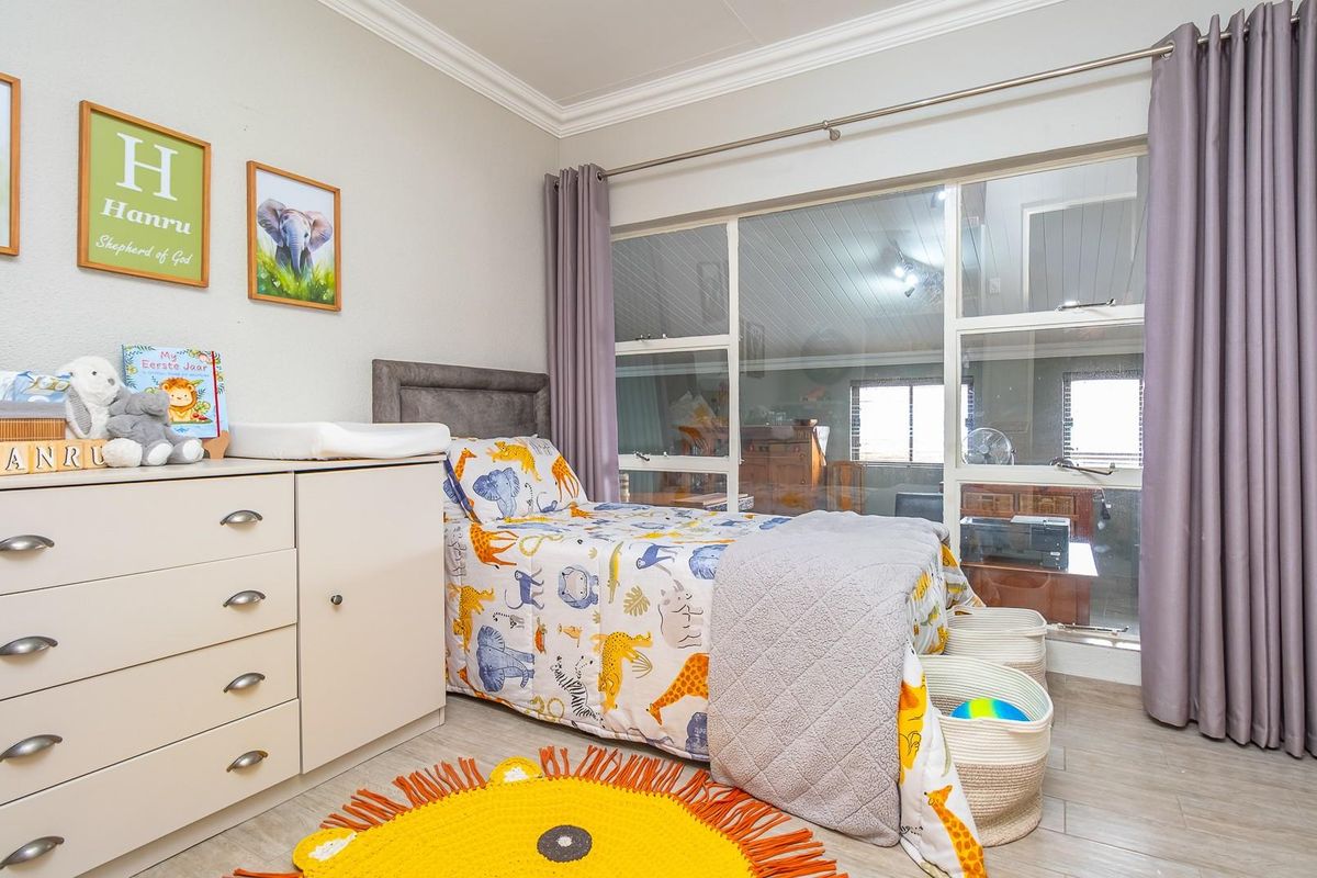 A well-maintained bedroom featuring large windows with curtain tracks, crown molding, and built-in cabinetry, offering a bright and functional living space.