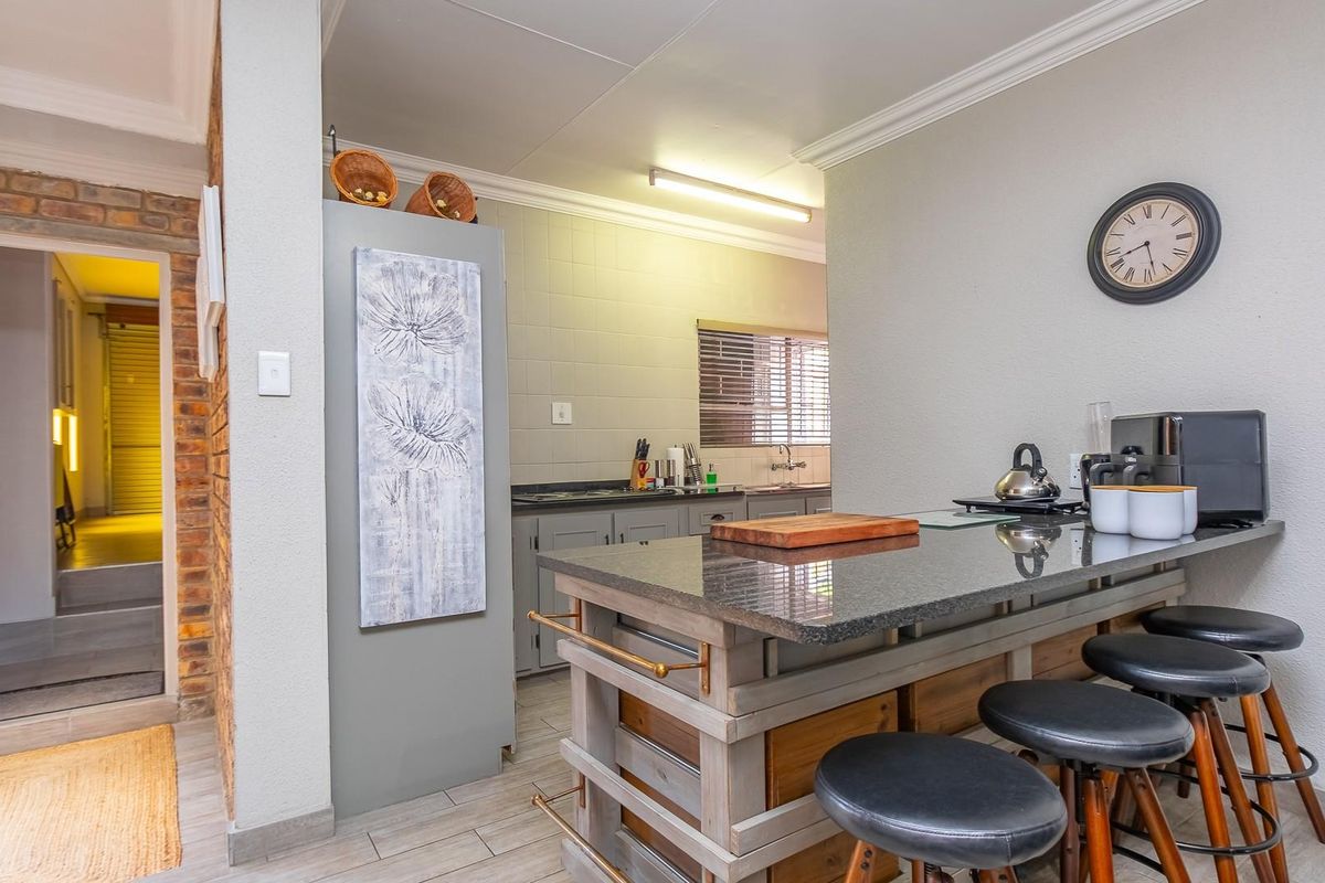 A functional kitchen featuring a granite-topped breakfast bar, tiled flooring, and neutral cabinetry, providing a practical layout for daily meal preparation.