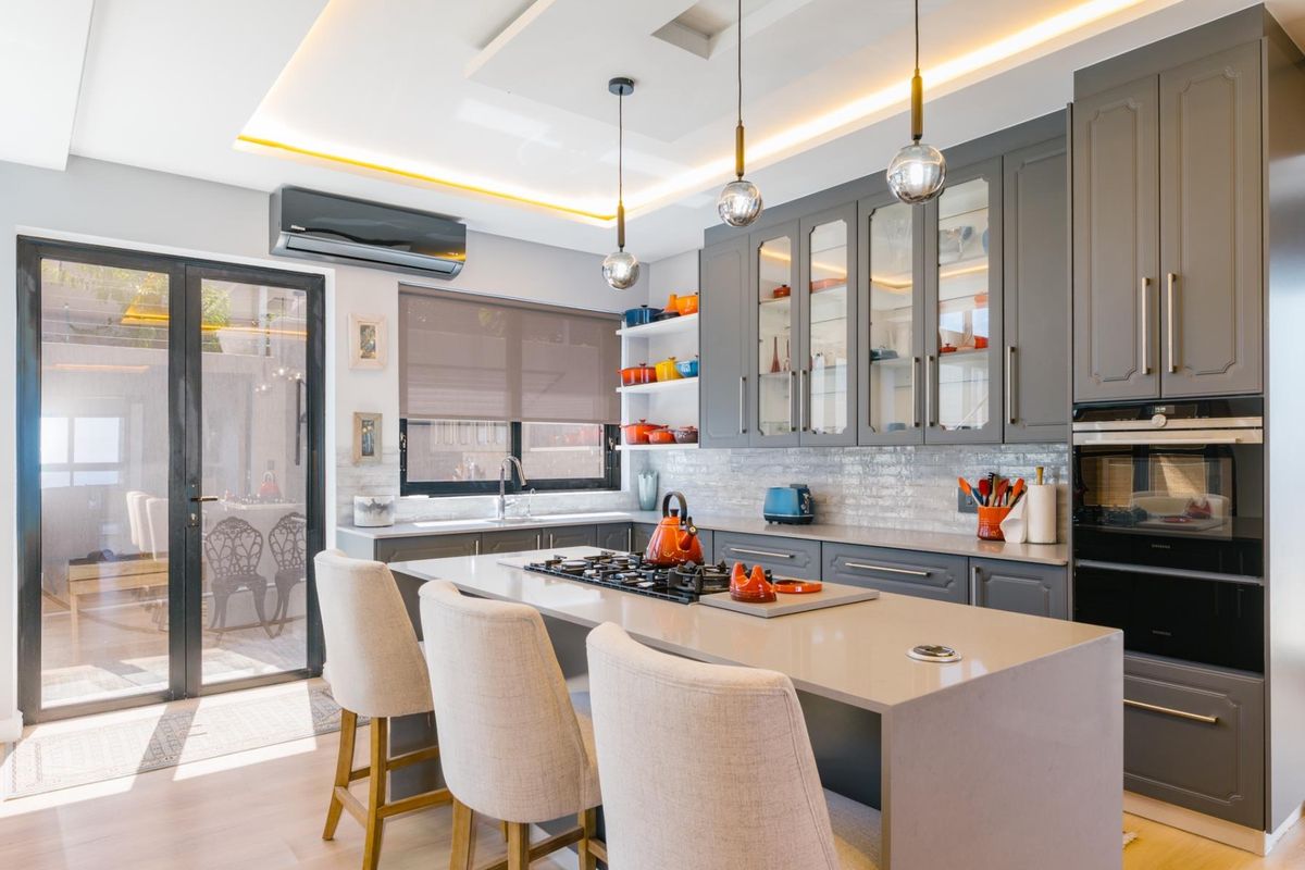 Modern kitchen featuring grey cabinetry, stone countertops, a central island with a built-in gas hob, integrated oven, and recessed ceiling lighting.