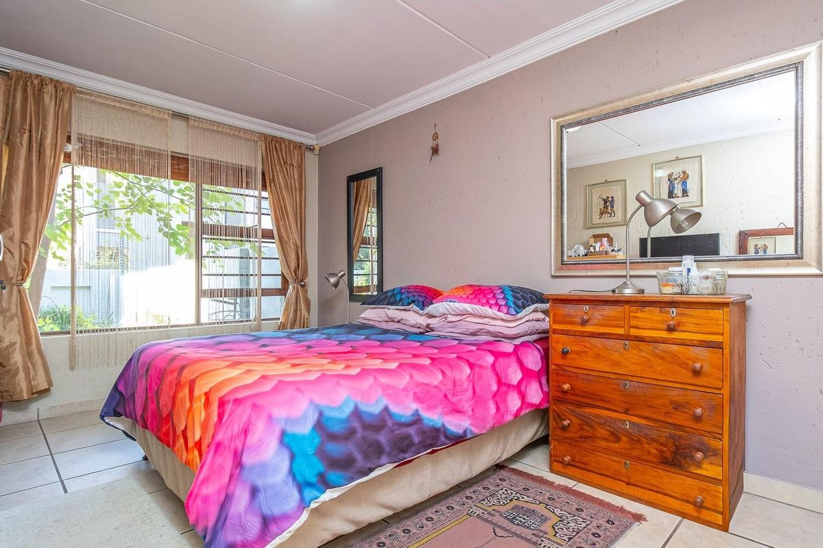 A bedroom featuring tiled flooring, large window with natural light, and crown molding detail.