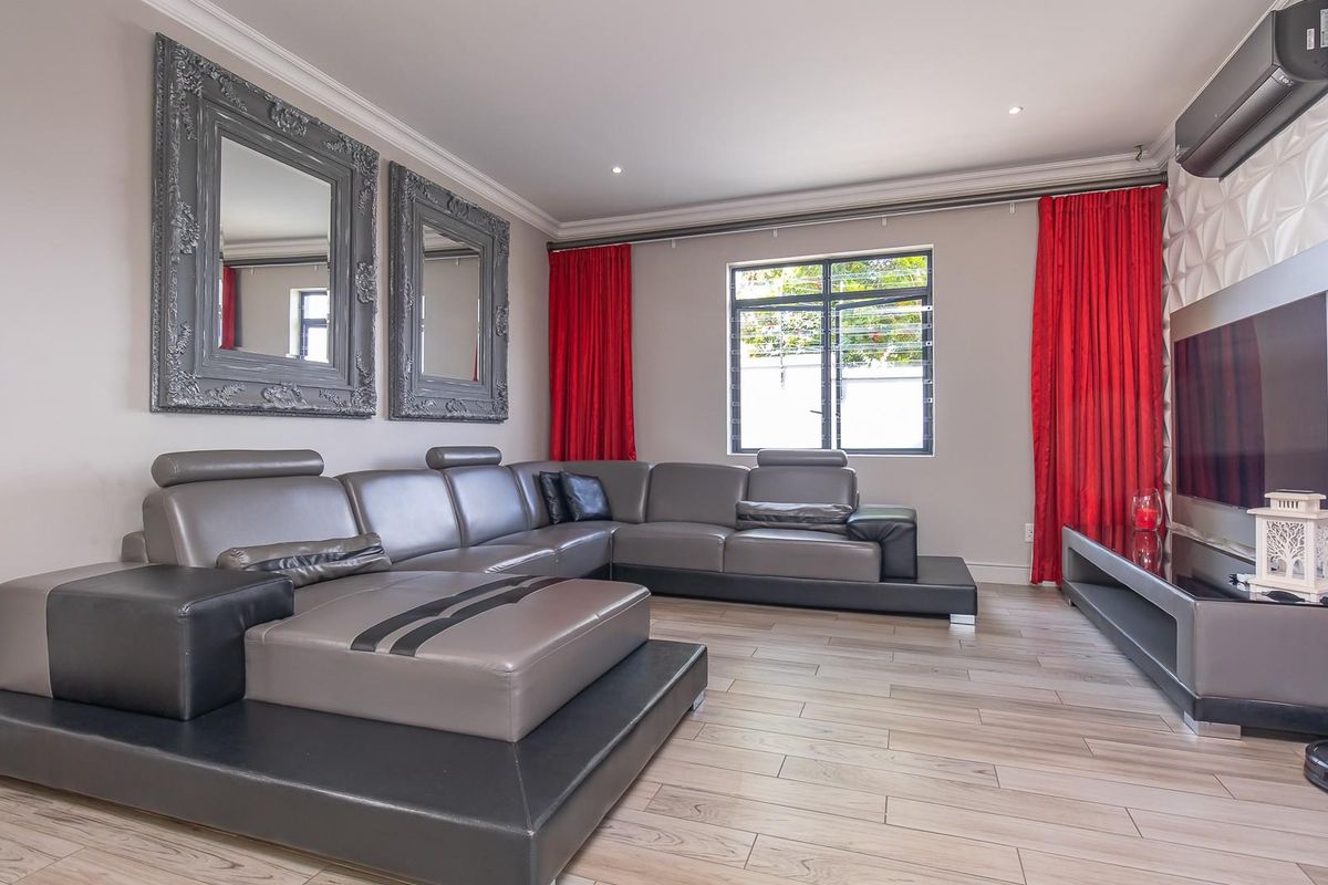A modern living room featuring wood-look tile flooring, recessed ceiling lighting, a textured feature wall, and a wall-mounted air conditioning unit.