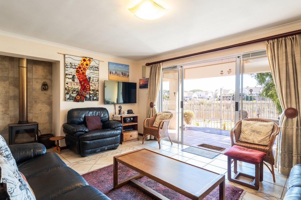 Spacious living room featuring a freestanding fireplace, tiled flooring, and large sliding glass doors providing direct access to the outdoor patio area.