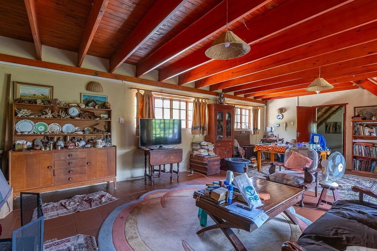 Spacious living area featuring exposed timber beam ceilings, tiled flooring, and a built-in fireplace, offering a rustic and character-filled atmosphere.