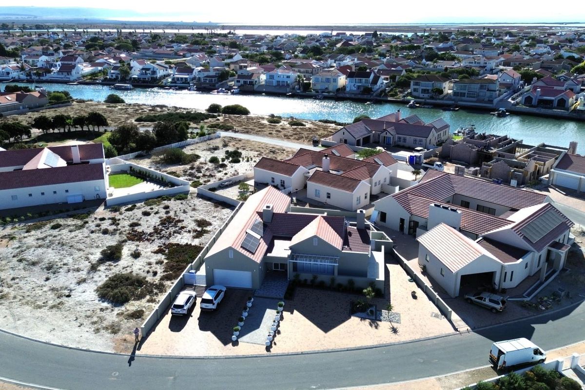 Aerial view of a residential property in a coastal estate, featuring tiled roofs, paved driveways, and proximity to the canal.