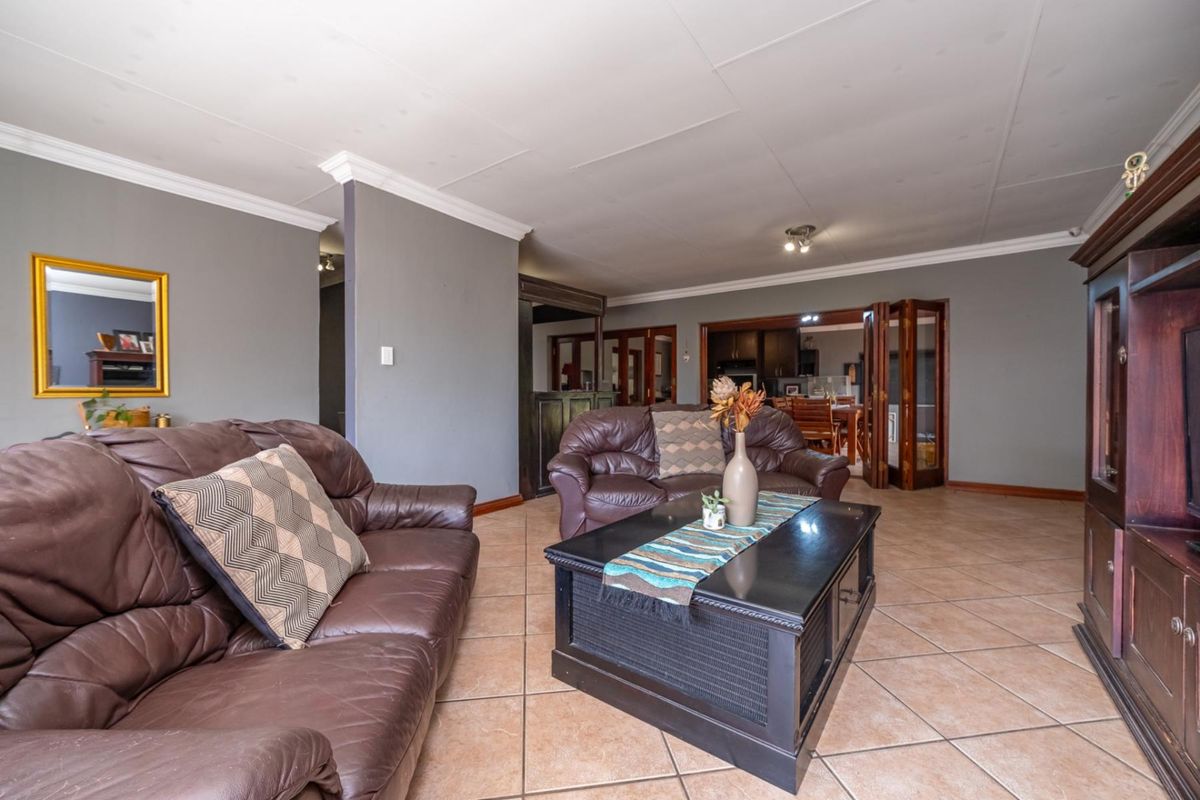 Spacious living area featuring tiled flooring, crown molding, and double glass doors leading to the dining room.