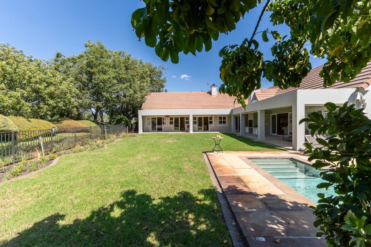 A spacious rear garden featuring a swimming pool, paved patio area, and well-maintained lawn, providing an ideal space for outdoor relaxation and entertainment.