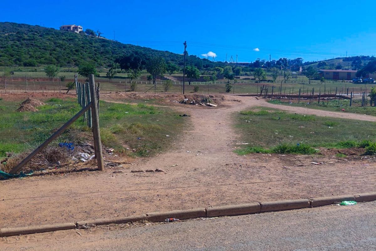 A vacant residential plot featuring natural terrain, wire fencing, and direct street access, offering a blank canvas for future development.