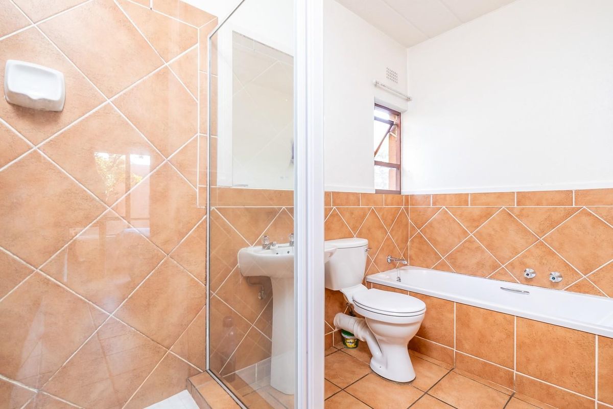 A functional bathroom featuring a shower enclosure, pedestal basin, toilet, and a built-in bathtub with tiled surround.