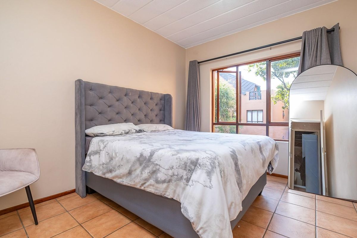 A bedroom featuring tiled flooring, a large window with curtain tracks, and a panelled ceiling.