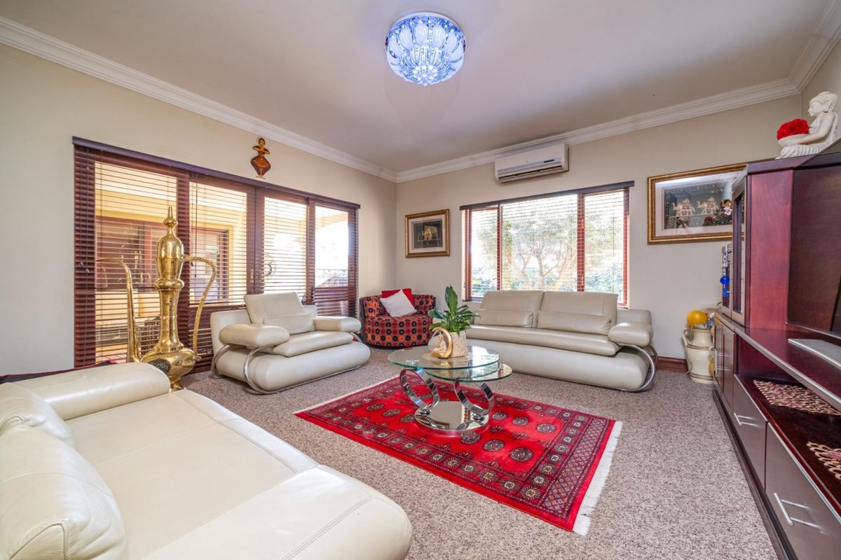 A comfortable living room featuring large windows with timber blinds, crown molding, and a wall-mounted air conditioning unit.