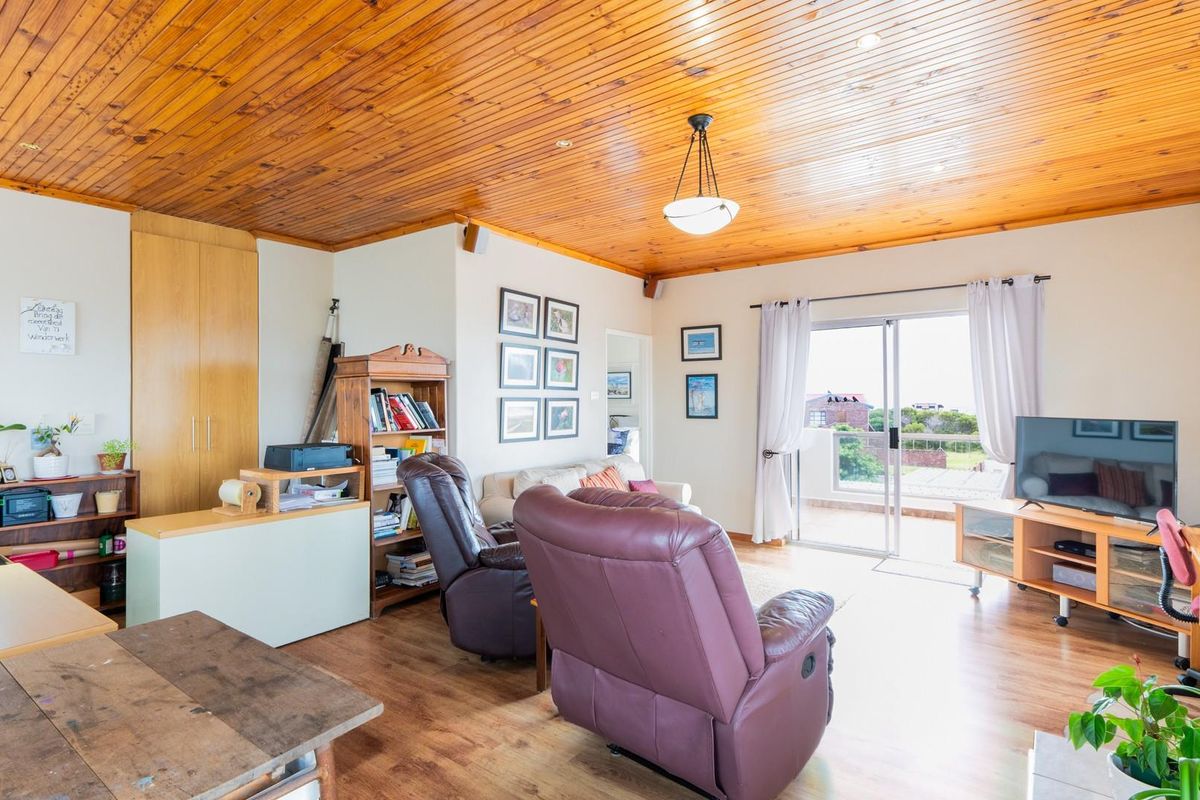 Spacious living room featuring a warm timber-clad ceiling, laminate flooring, and sliding glass doors providing direct access to an outdoor balcony area.