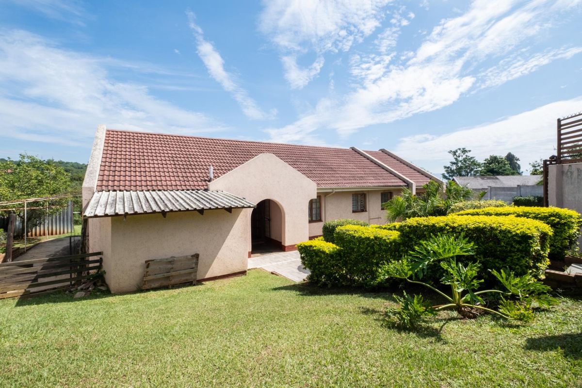 A view of the rear exterior of the house, featuring a tiled roof, arched entrance, and a well-maintained garden area.