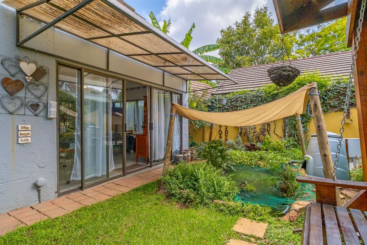 A private rear garden featuring a small pond, a covered patio area with sliding glass doors, and established perimeter landscaping.