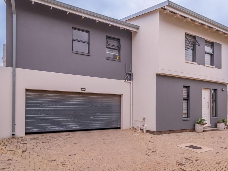 Modern double-storey townhouse exterior featuring a paved driveway, double garage, and contemporary grey and white facade finishes.