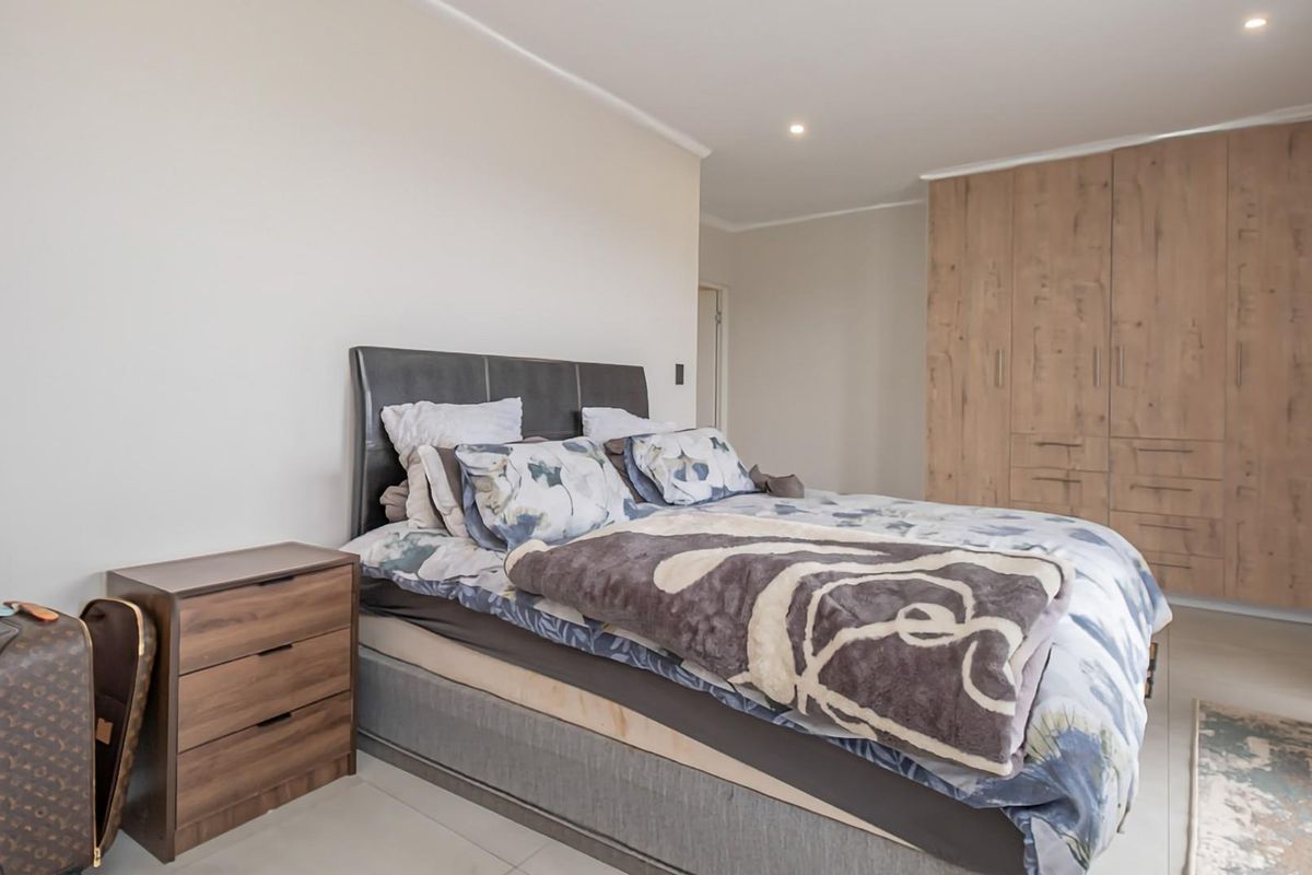 A well-maintained bedroom featuring neutral walls, tiled flooring, recessed downlighting, and ample built-in wooden cabinetry for storage.