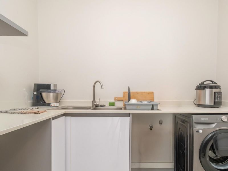 A functional laundry area featuring a stainless steel sink, countertop space, and dedicated plumbing connections for a washing machine.