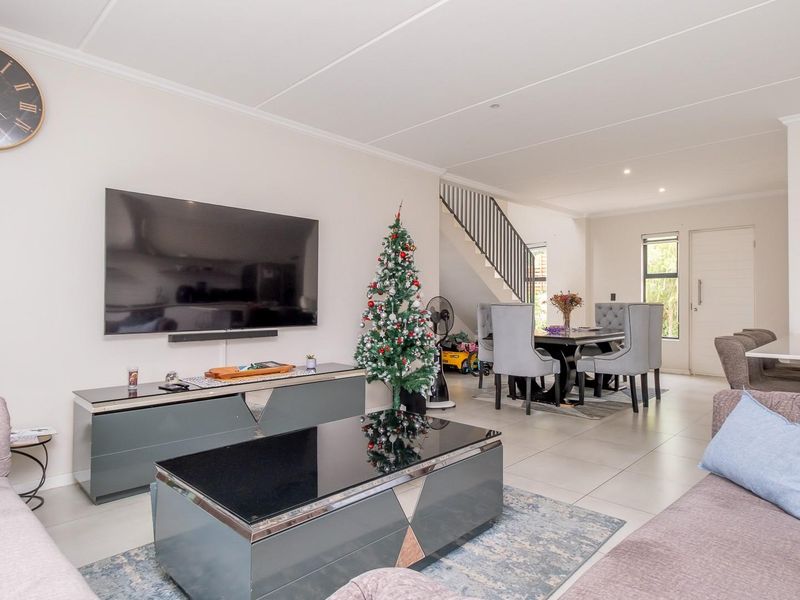 Spacious open-plan living and dining area featuring tiled flooring, a modern staircase, and a breakfast bar, creating a bright and functional layout.