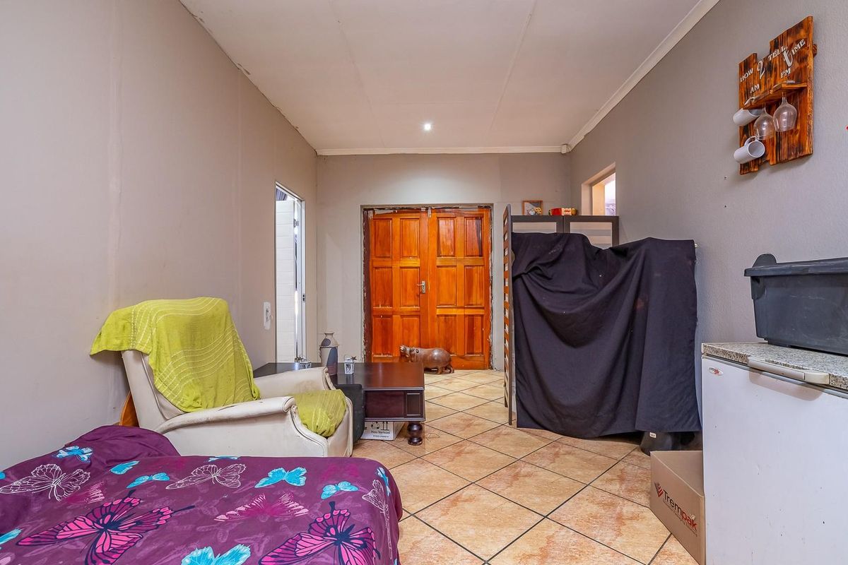 A functional living area featuring tiled flooring and double wooden doors leading to an adjacent space.
