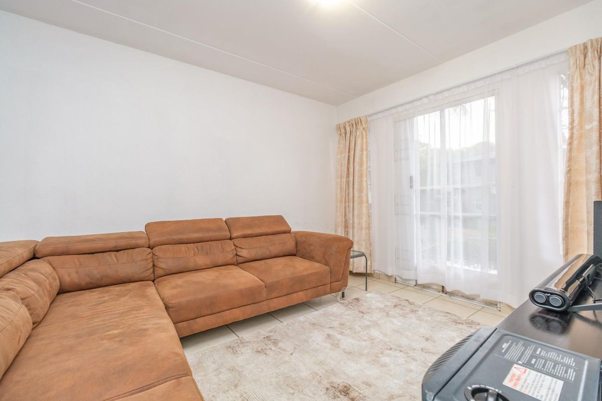 A living room featuring tiled flooring and a sliding glass door providing access to the exterior.
