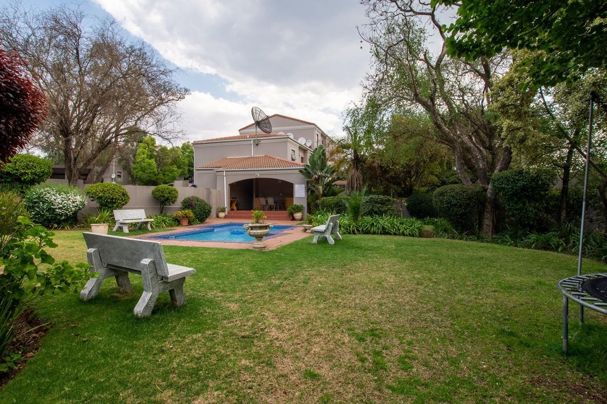 A spacious rear garden featuring a swimming pool, a covered patio area, and established landscaping, providing a private outdoor retreat.