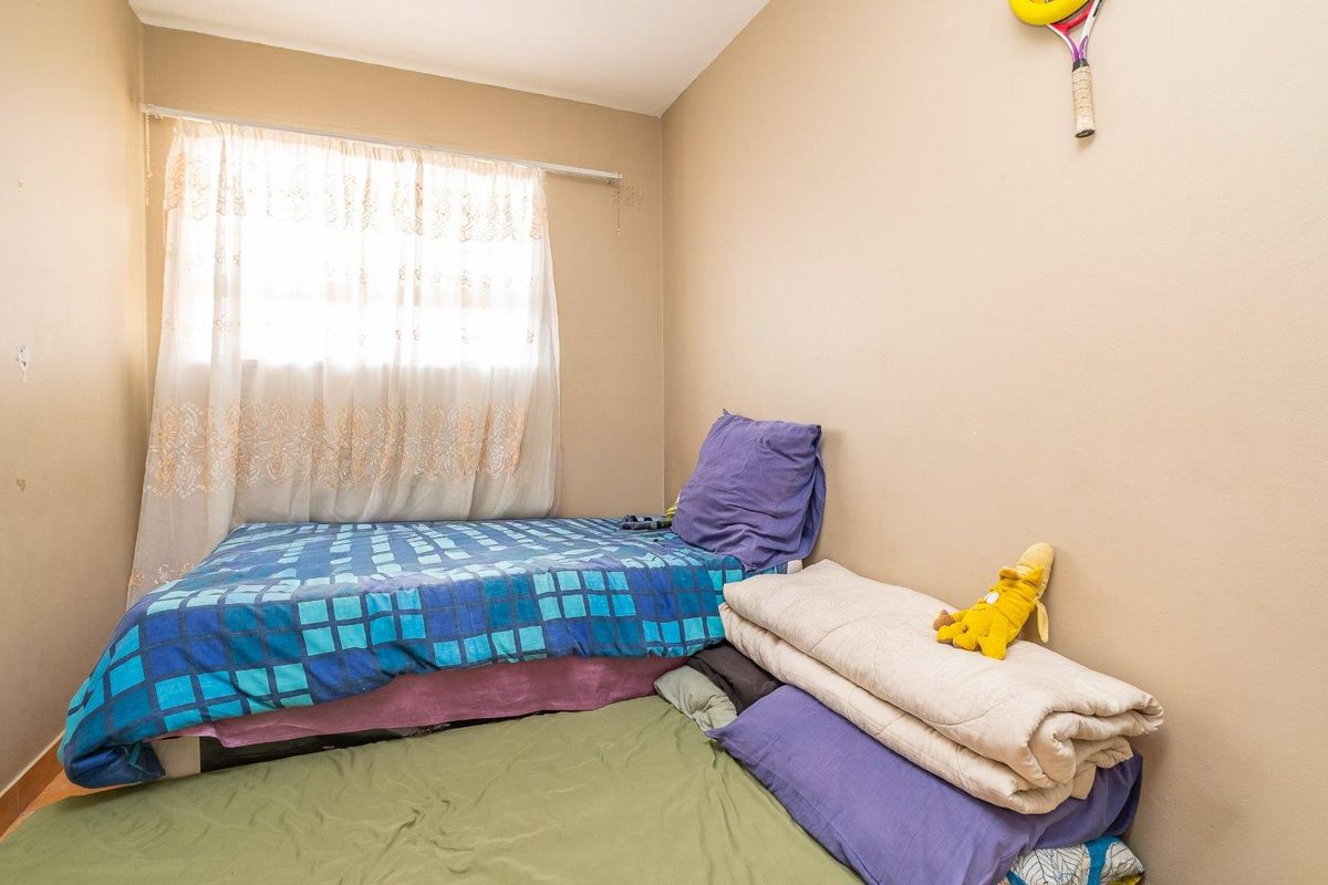 A compact bedroom featuring a window with curtain and neutral wall finishes, suitable for a single bed or study area.