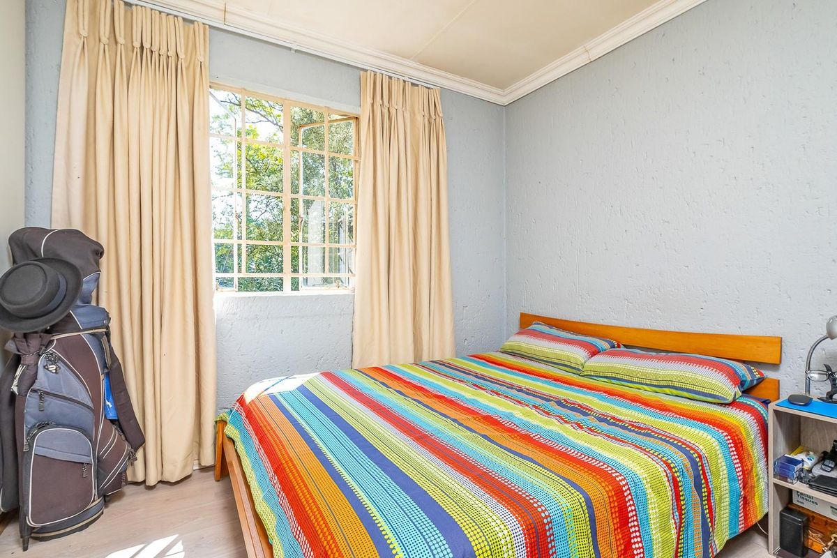A standard bedroom featuring a window with security bars, built-in cupboard, and textured wall finishes.