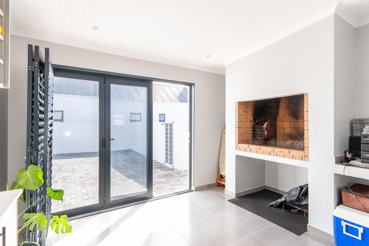 Bright living area featuring a built-in brick fireplace and large sliding glass doors opening onto a paved rear courtyard.