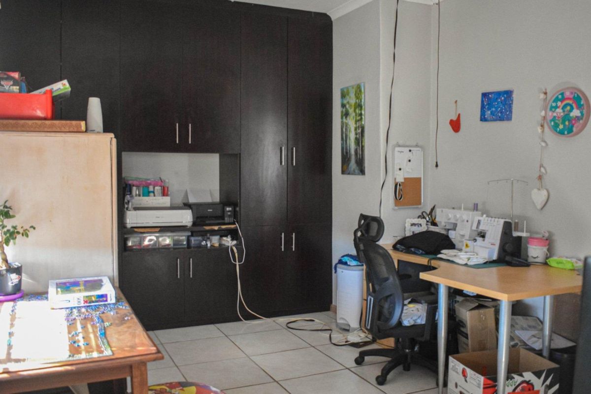 A functional bedroom or home office space featuring dark built-in cabinetry and tiled flooring, offering versatile storage and workspace potential.