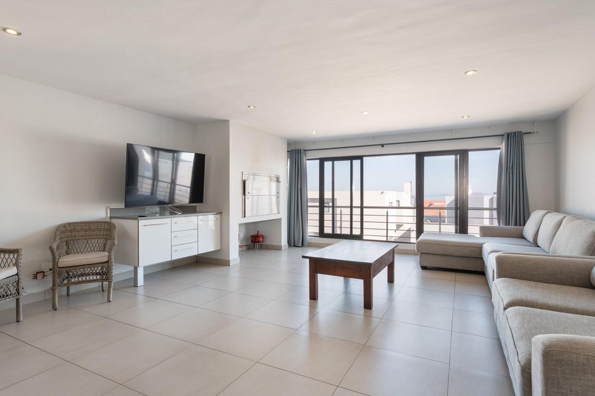 Spacious living area featuring large sliding glass doors, tiled flooring, recessed lighting, and a built-in indoor braai fireplace.