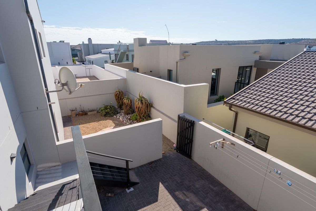 An elevated view of a private courtyard area featuring paved flooring, boundary walls, and a small landscaped garden section.